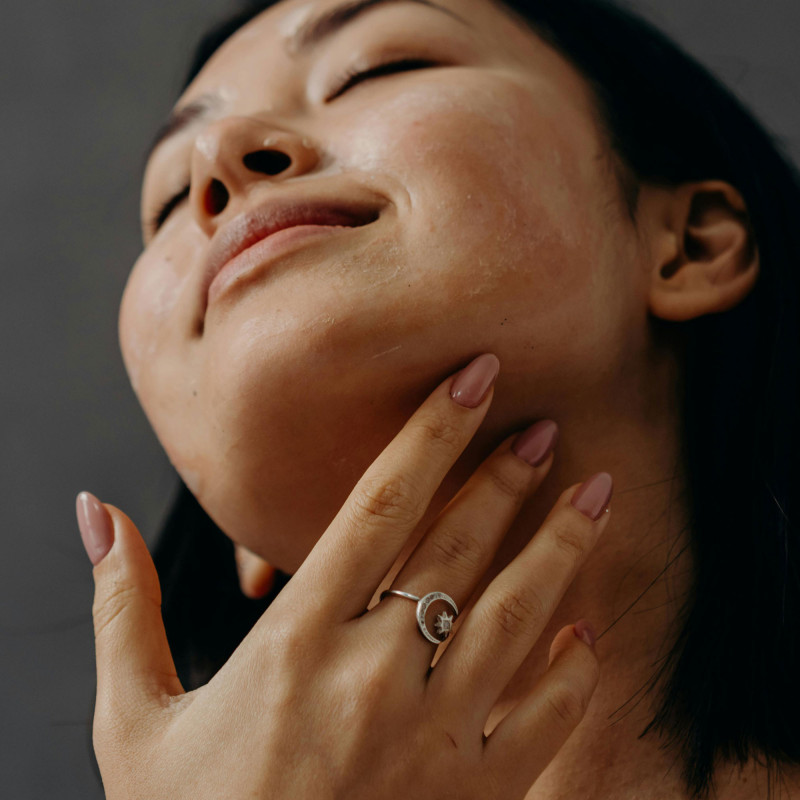 Une femme qui a fait sa manucure et qui applique son soin pour le visage.