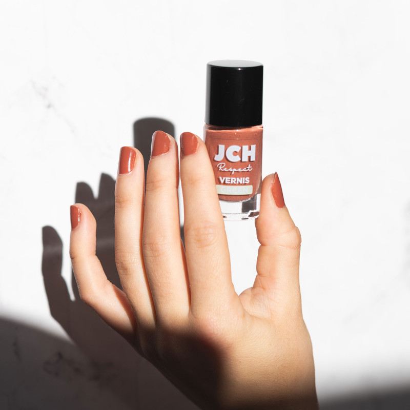 Un main qui tient le vernis terracota de chez JCH Respect